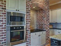 a brick wall in a kitchen with an oven and microwave