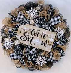 a black and white wreath with snowflakes on it that says, let it snow