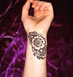 a woman's arm with a henna tattoo on it and a purple velvet background