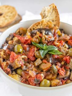 a white bowl filled with olives and bread