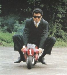 a man in suit and sunglasses riding a motorcycle