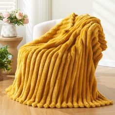 a large yellow blanket sitting on top of a wooden floor next to a white chair