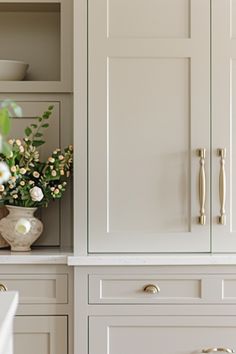 a vase with flowers in it sitting on top of a counter next to some cupboards