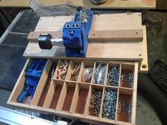 an open drawer with screws and nails in it on top of a workbench