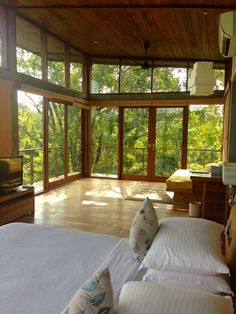 two beds in a room with windows and wood flooring next to each other on a cell phone