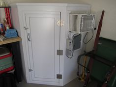 a white cabinet sitting in the corner of a room next to a wall mounted air conditioner