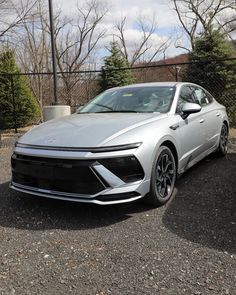 a silver car parked in front of a fence