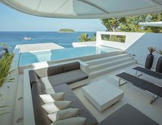 an outdoor living area with couches and tables overlooking the ocean