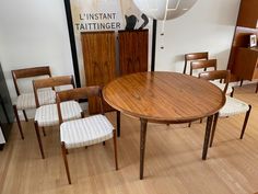 a table and chairs in a room with wood flooring next to a large poster on the wall