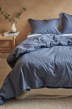 a bed with blue sheets and pillows in a bedroom