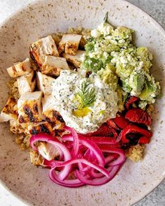 a white bowl filled with meat and veggies on top of a marble table