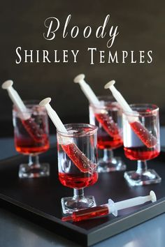 four glasses filled with red liquid sitting on top of a black tray next to a toothbrush