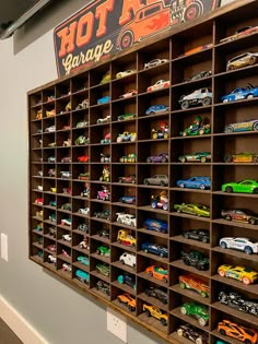 toy cars are lined up on shelves in a room that has a hot wheels garage sign above them