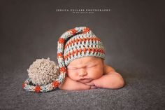 a newborn baby wearing a crocheted hat and holding a stuffed animal