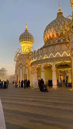 people are sitting and standing around in front of some large white buildings with gold domes