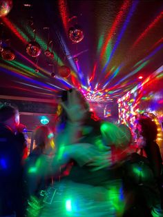 people dancing at a party with colorful lights