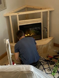 a man sitting on the floor in front of a fire place with tools around him