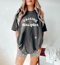 "♥ Looking for the perfect blend of comfort & style? Add one of our trendy Comfort color tees to your wardrobe! This design features a \"Raising Disciples\" graphic, perfect for the Christian mama wanting to display her faith! This design can also be purchased in a cozy sweatshirt option here! https://etsy.me/3SrbEpr ♥ About Printing/Garment: All of our apparel is printed using DTG printing in which the design is printed directly onto the garment which reduces cracking and peeling over time when cared for properly. Graphics are NOT vinyl. :) This shirt is a high-quality Comfort Color garment-dyed tee that comes in a variety of gorgeous hues for a lived-in vintage look. It is made of 100% cotton with a heavyweight feel for durability, but an unmatched softness for comfort! Comfort color gar Christian Mom Shirts, Christian Tshirts Designs Woman, Mama Shirt Ideas, Christian Tees Women, Raising Disciples, Mom Group, Christian Tshirt, Faith Tees, Christian T Shirt