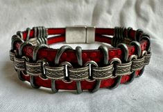 This rugged unisex bracelet looks great on just about anybody! This piece is handmade of polka dot embossed red strap leather, silver chain, metallic silver leather cord and finished with a metallic clasp for easy on and off. Fits a size 6.5 inch wrist snugly, but not tight.  Please note sizing! To measure your wrist, take a tape measure and wrap it snugly (with no slack) around your wrist. (I build in extra space for it to hang/fit properly.) If you have questions, please contact me! I'm happy to make a custom size for you. Vintage Silver Leather Bracelet As Gift, Silver Metal Bracelets With Leather Strap, Silver Bracelets With Leather Strap, Handmade Metal Leather Bracelet For Gift, Adjustable Red Bracelet With Leather Strap, Handmade Adjustable Red Leather Bracelet, Handmade Red Leather Bracelet, Vintage Silver Metal Bracelet, Adjustable Red Leather Strap Bracelet