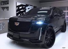 the front end of a black suv in a showroom with white lettering on it