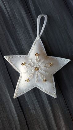 a white star ornament hanging from a string on a wooden surface with beads