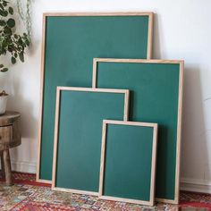 three frames sitting next to each other in front of a wall with a potted plant