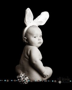 a baby wearing a white bunny ears headband on top of it's back