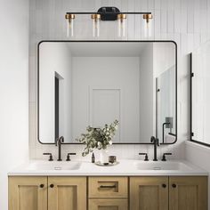 a bathroom vanity with two sinks and a large mirror above it, along with lights on the wall