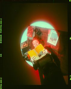 a woman reading a book in front of a round window with pictures on it and around her