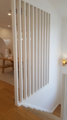 an empty room with white walls and wooden floors is seen from the doorway to the dining area