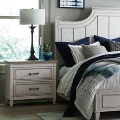 a white bed sitting next to a night stand with two lamps on top of it