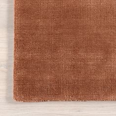 a brown rug on top of a white wooden floor next to a vase with flowers