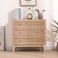 a wooden dresser with wicker drawers next to a plant and clock on top of it