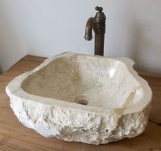 a stone sink sitting on top of a wooden table next to a faucet