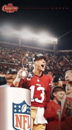 a football player holding a trophy in front of a crowd