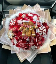 a christmas wreath with teddy bears and candy canes in the center is sitting on top of a car seat