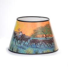 a lamp shade with a painting of horses and farmer on it's side, against a white background