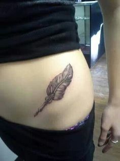 a woman's stomach with a feather tattoo on it