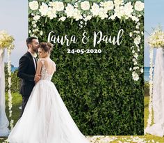 a bride and groom standing in front of an outdoor wedding ceremony backdrop with white flowers