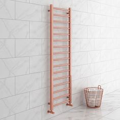 an orange heated towel rack next to a basket on the floor in front of a white tiled wall