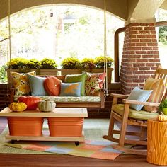 the porch is decorated with pumpkins and fall colors, such as an orange chair