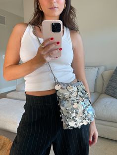 a woman taking a selfie with her cell phone while wearing black and white pants