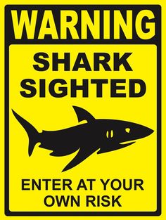 a warning sign that warns people to beware of sharks