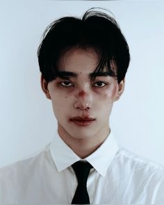 a young man wearing a white shirt and black tie with blood on his face,