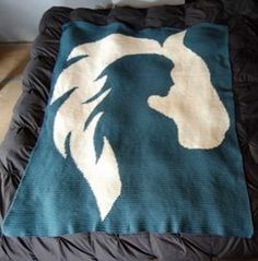 a blue and white blanket sitting on top of a black bed next to a pillow