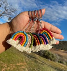 a hand holding a bunch of multicolored earrings in front of a blue sky