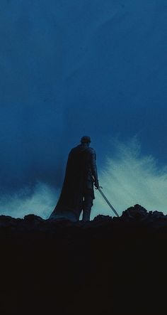 a man standing on top of a hill next to a giant wave