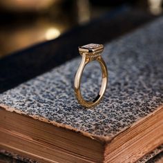 a gold ring sitting on top of a book with a black diamond in it's center