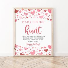 a pink and red baby socks print with hearts on the floor next to a wooden frame