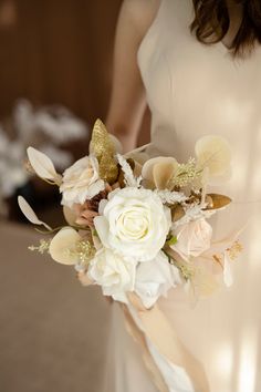 a woman holding a bouquet of flowers in her hand and wearing a white dress with gold sequins on it